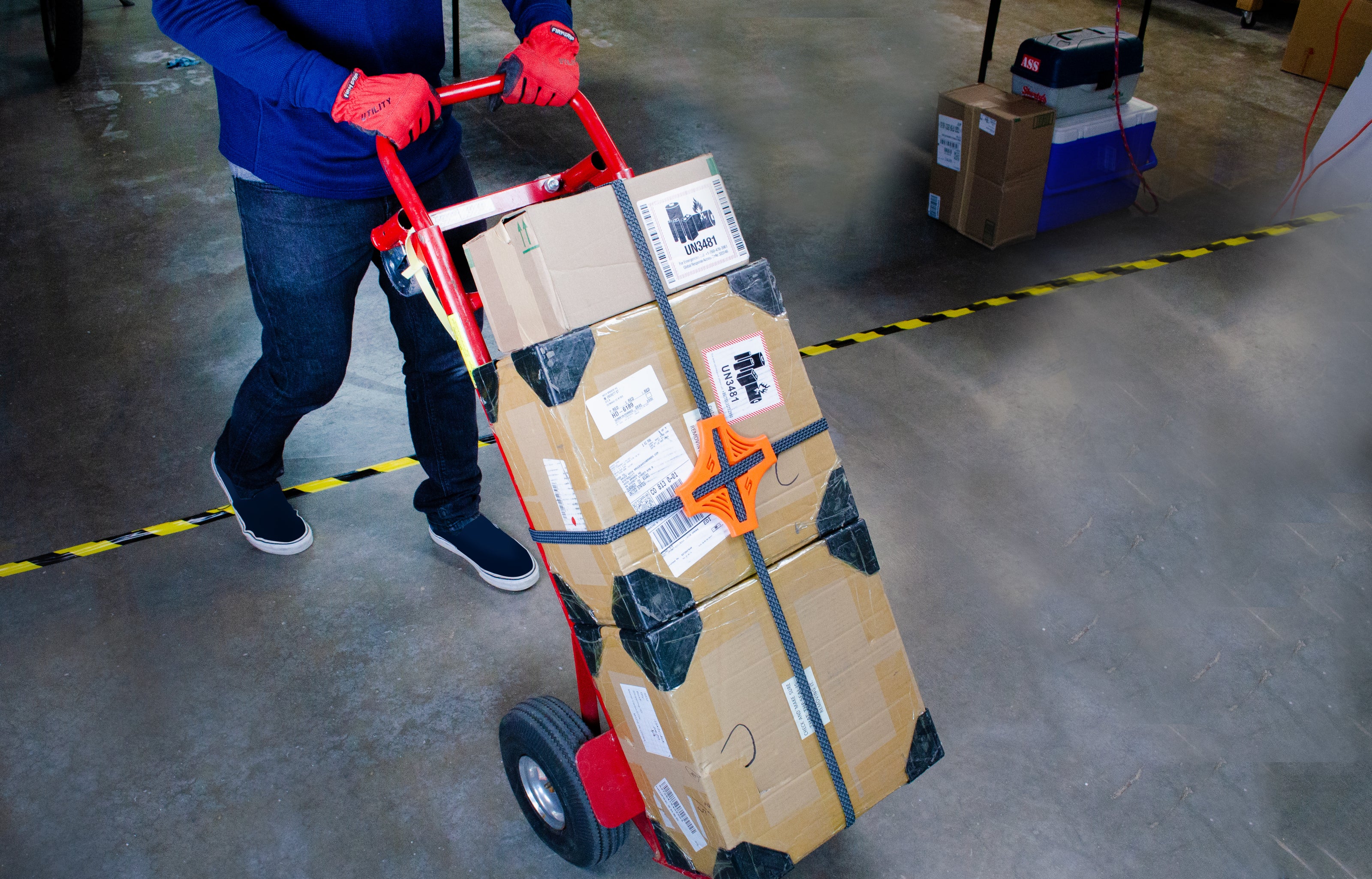 Orange Tack Strap securing stacked cardboard boxes on moving dolly