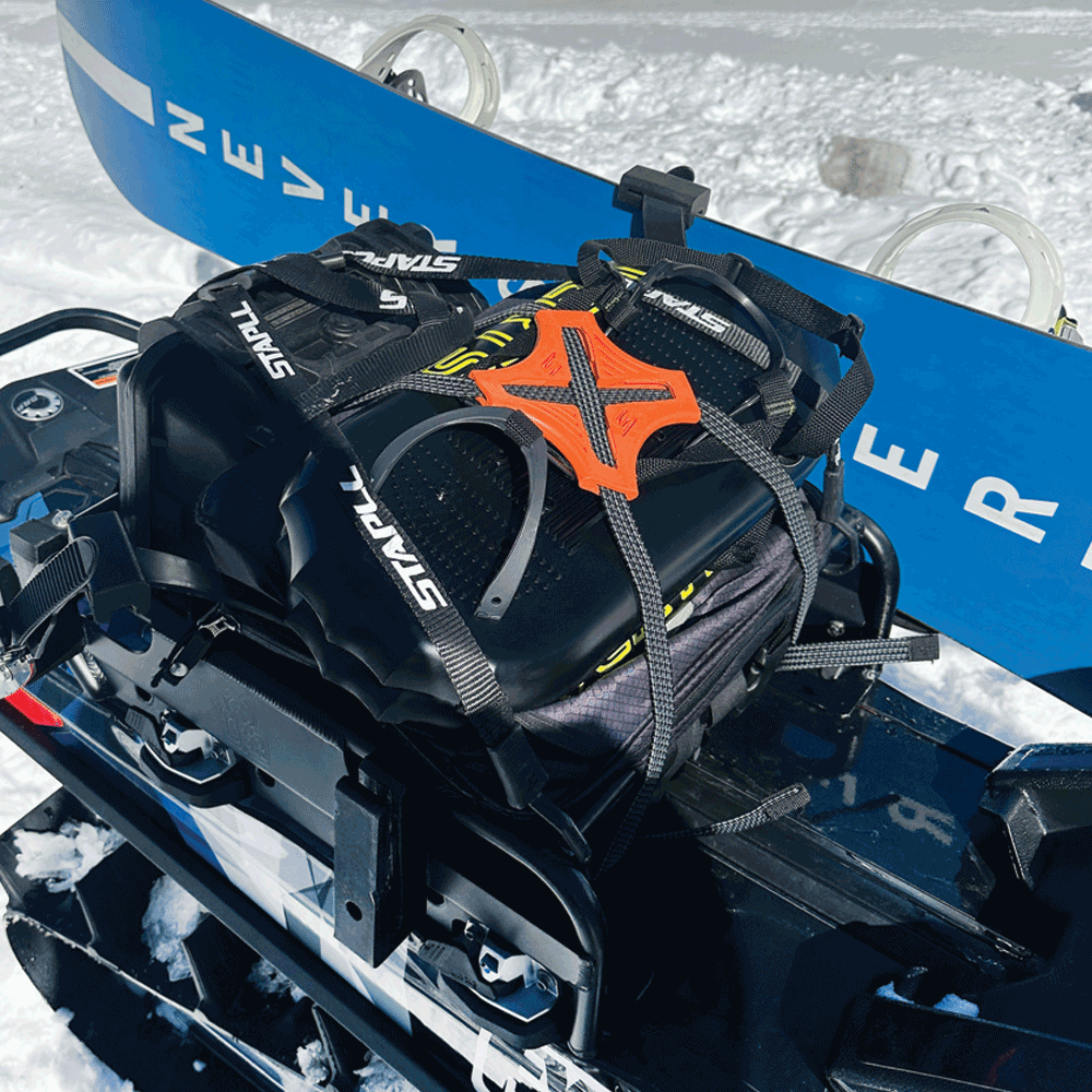 Camo Tack Strap securing black bag on snowmobile in snowy NZ conditions